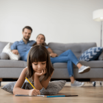 Parents on couch watching daughter draw